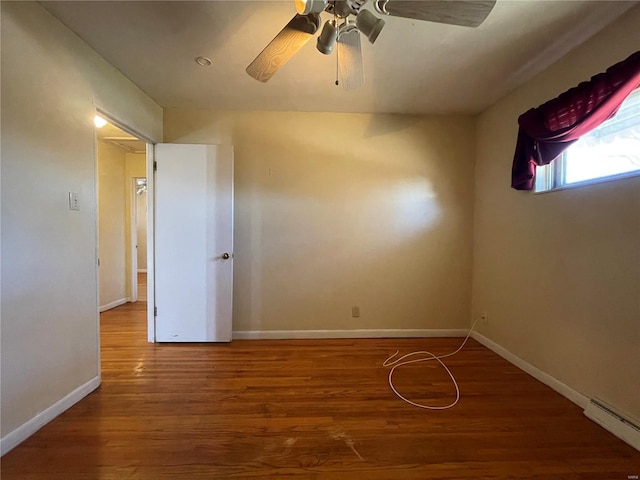 empty room featuring ceiling fan, wood finished floors, baseboards, and a baseboard radiator