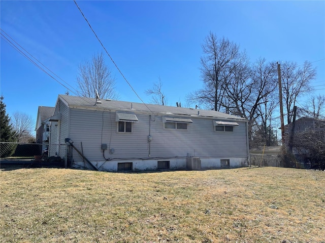 rear view of house featuring central air condition unit, a lawn, and fence