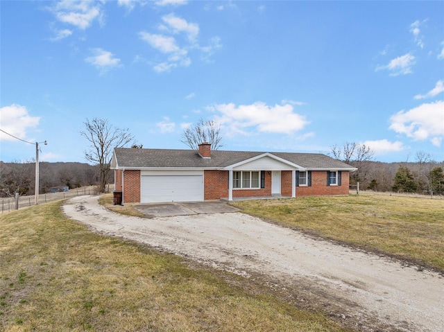 single story home with driveway, a chimney, a front lawn, a garage, and brick siding