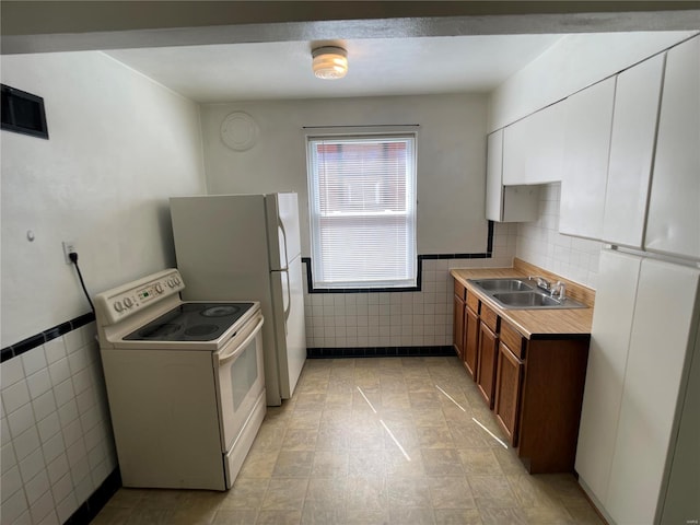 kitchen with a sink, white cabinetry, white electric stove, tile walls, and brown cabinetry