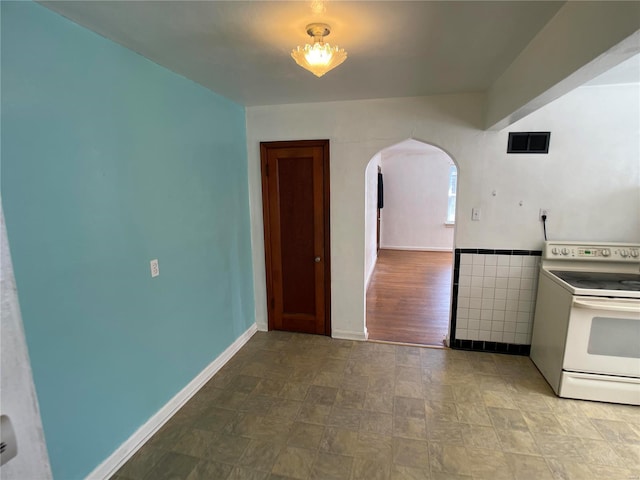 kitchen with white range with electric cooktop, visible vents, arched walkways, and baseboards