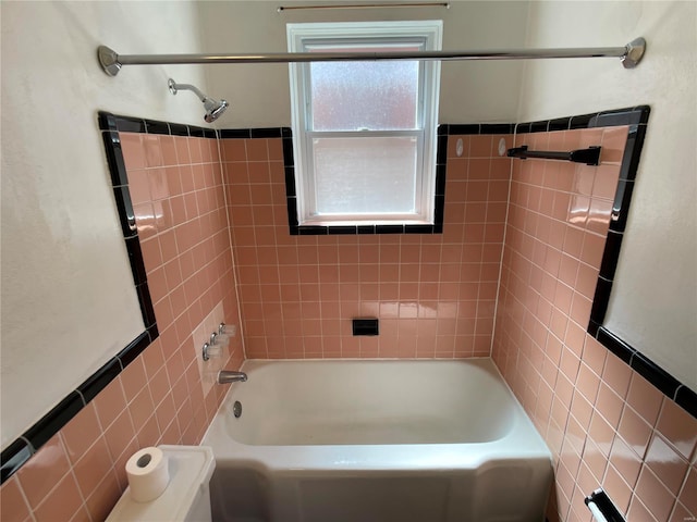 bathroom with bathing tub / shower combination and tile walls