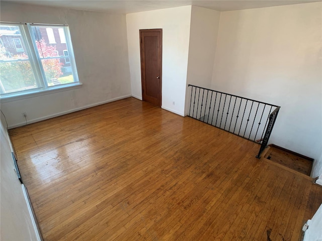 spare room with baseboards and wood-type flooring