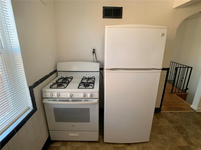 kitchen featuring white appliances, tile walls, and visible vents