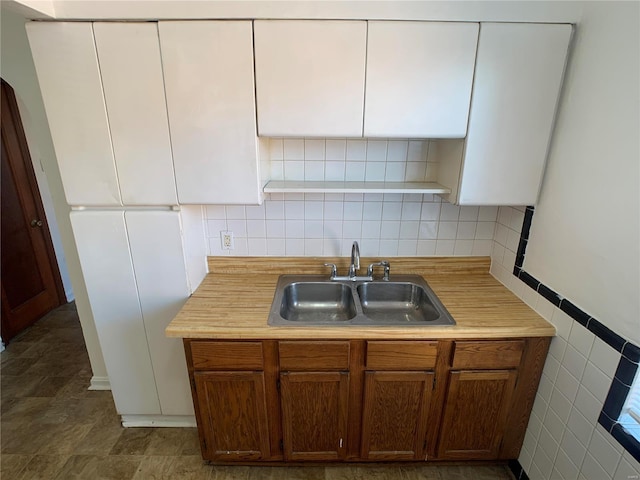 kitchen with light countertops, white cabinets, tile walls, and a sink