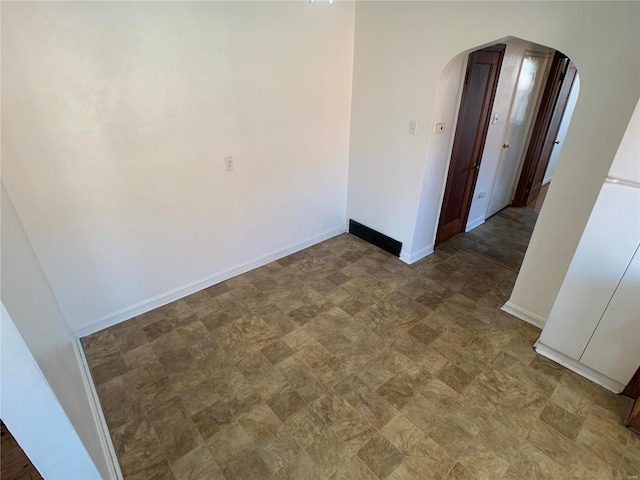 empty room featuring baseboards and arched walkways