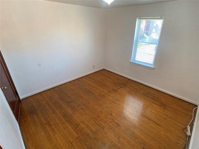 spare room featuring baseboards and wood-type flooring