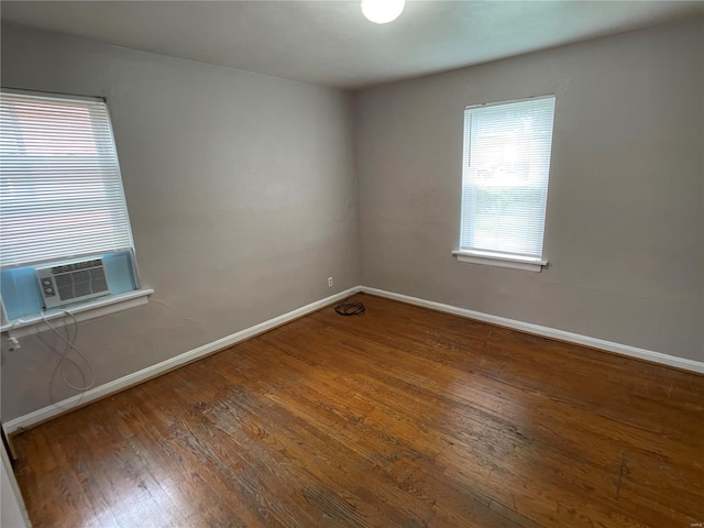 empty room featuring cooling unit, baseboards, and hardwood / wood-style floors