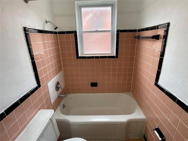 full bath with toilet, tile walls, and bathing tub / shower combination