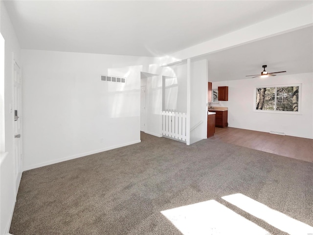 unfurnished living room with visible vents, carpet floors, baseboards, and a ceiling fan