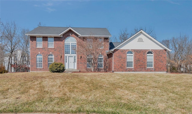 colonial home featuring brick siding and a front yard