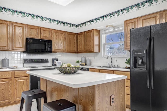 kitchen featuring a kitchen island, light countertops, decorative backsplash, black appliances, and a sink