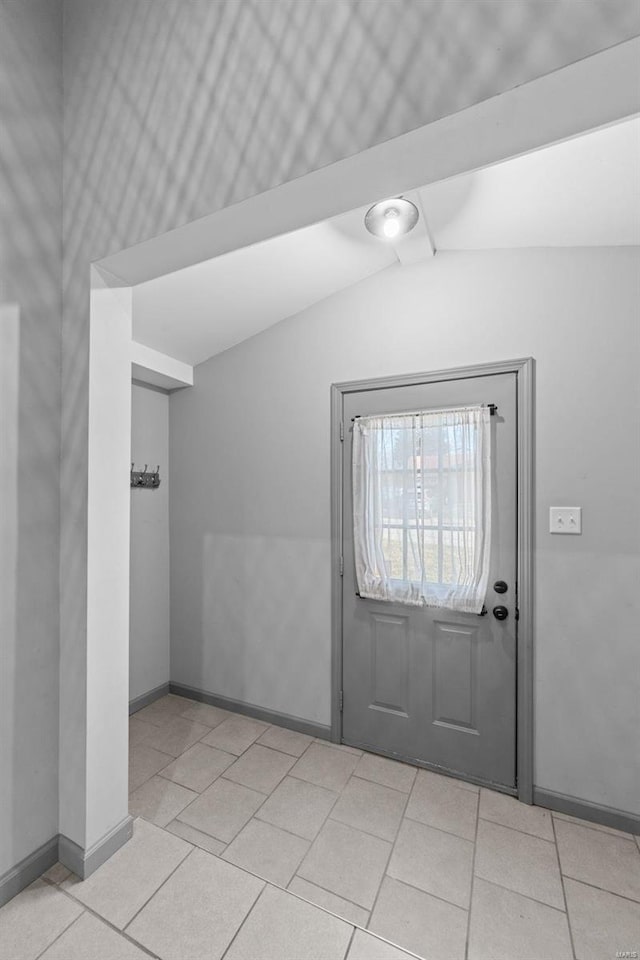 entryway with light tile patterned floors, baseboards, and vaulted ceiling