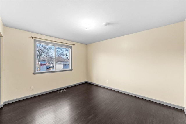 unfurnished room featuring visible vents, baseboards, and dark wood-style floors