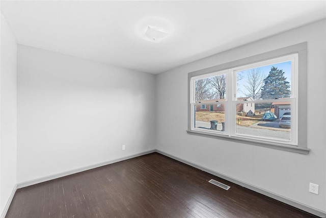 spare room with dark wood finished floors, baseboards, and visible vents