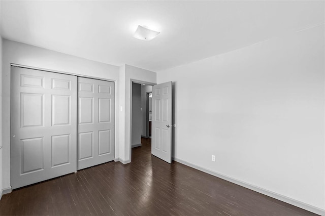 unfurnished bedroom featuring a closet, baseboards, and wood finished floors