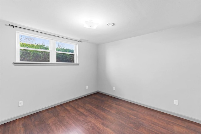 unfurnished room with baseboards and dark wood-style floors