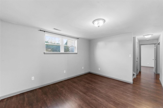 unfurnished room featuring wood finished floors, visible vents, and baseboards