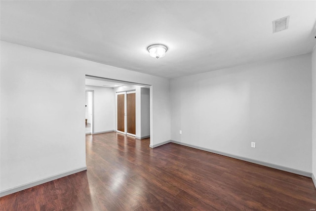 unfurnished room with wood finished floors, visible vents, and baseboards