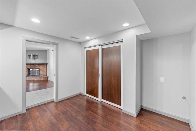 unfurnished bedroom with recessed lighting, a closet, a brick fireplace, and wood finished floors