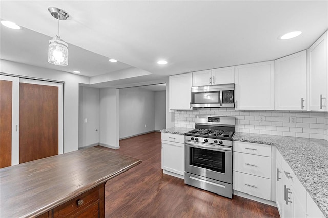 kitchen featuring light stone countertops, dark wood finished floors, decorative backsplash, appliances with stainless steel finishes, and white cabinetry