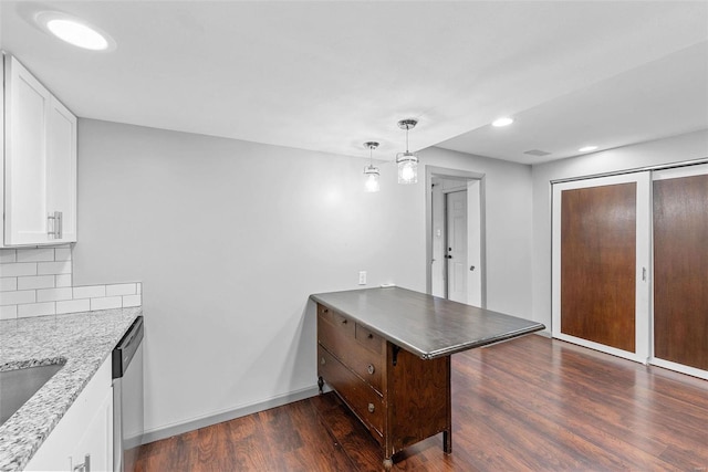 kitchen featuring white cabinetry, a peninsula, dark wood-type flooring, stainless steel dishwasher, and tasteful backsplash