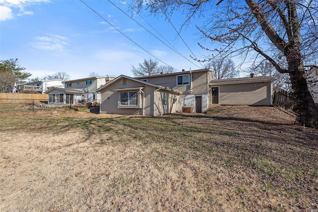 back of property with a lawn and fence