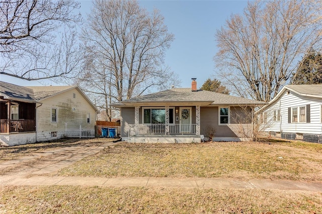 view of front of house with a front yard, a porch, and a chimney