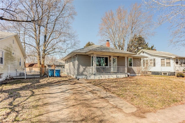 view of front of house featuring a porch, a chimney, and fence