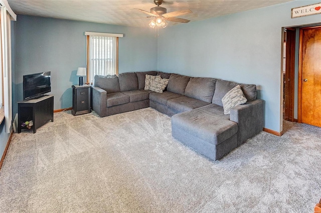 living area featuring carpet flooring, baseboards, and a ceiling fan