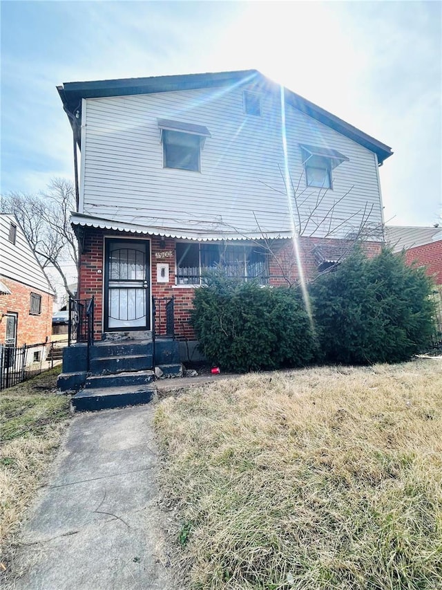 view of front of home with a front lawn, fence, and brick siding