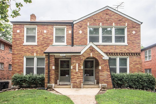 view of front facade featuring a front yard, brick siding, and a chimney