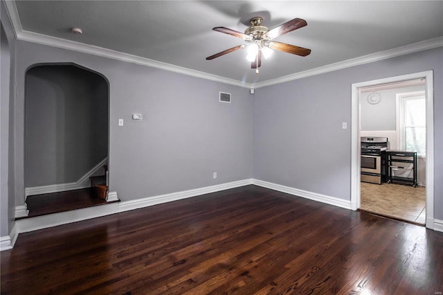 spare room featuring arched walkways, wood finished floors, visible vents, and ornamental molding