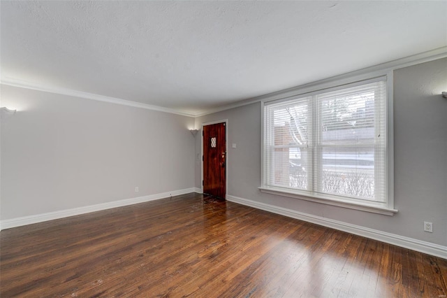 unfurnished living room featuring baseboards, wood-type flooring, and ornamental molding