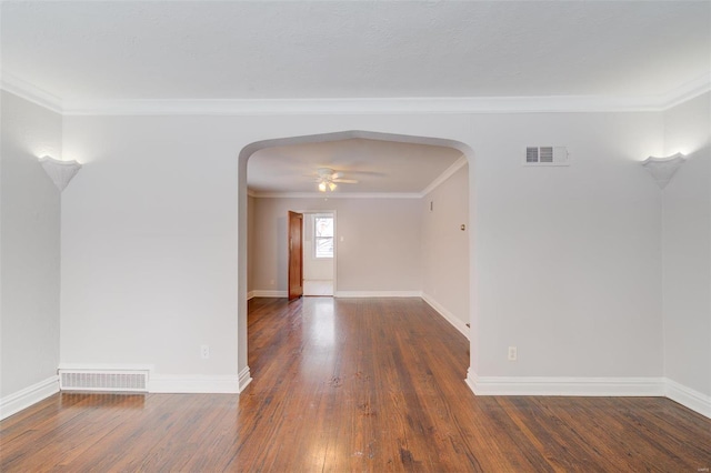 spare room with arched walkways, visible vents, baseboards, and hardwood / wood-style flooring