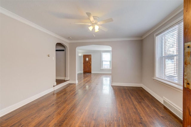 unfurnished room with dark wood-type flooring, arched walkways, visible vents, and baseboards