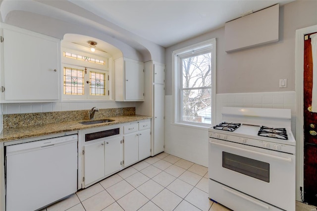 kitchen featuring white appliances, white cabinets, light tile patterned flooring, and a sink