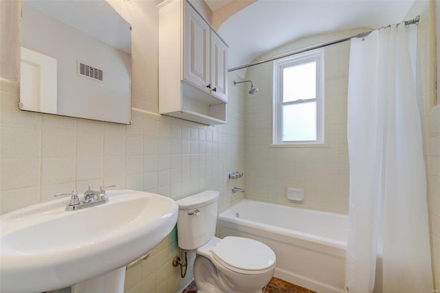 full bath featuring visible vents, a sink, shower / tub combo, tile walls, and toilet