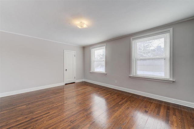 unfurnished room with crown molding, dark wood-style floors, and baseboards