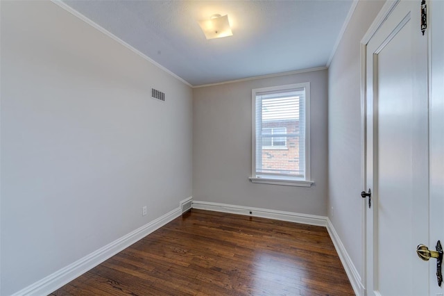 unfurnished room with dark wood finished floors, visible vents, crown molding, and baseboards