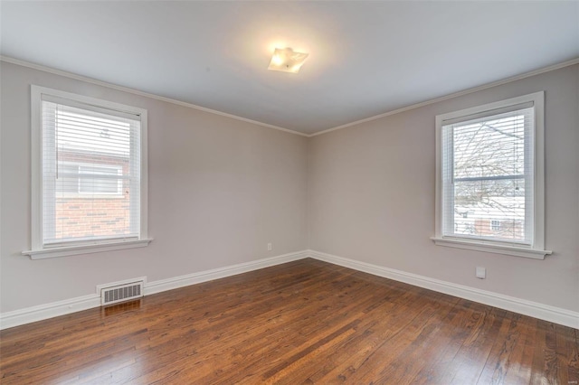 unfurnished room featuring dark wood-style floors, visible vents, baseboards, and ornamental molding