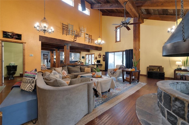 living area with beam ceiling, ceiling fan with notable chandelier, hardwood / wood-style flooring, baseboards, and wood ceiling