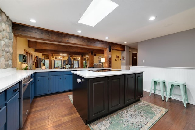 kitchen with blue cabinetry, a skylight, light countertops, dark wood-type flooring, and stainless steel dishwasher