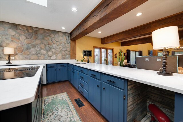 kitchen featuring blue cabinetry, dark wood finished floors, light countertops, black electric cooktop, and a sink