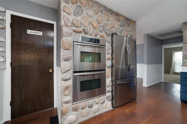 kitchen with wainscoting, visible vents, dark wood-style flooring, and stainless steel appliances