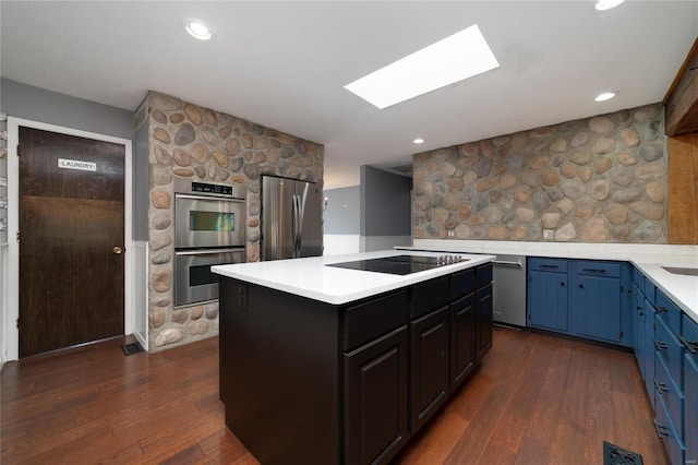 kitchen with a kitchen island, appliances with stainless steel finishes, dark wood finished floors, and light countertops