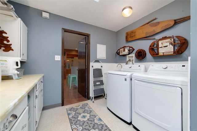 laundry room featuring cabinet space, light floors, and separate washer and dryer