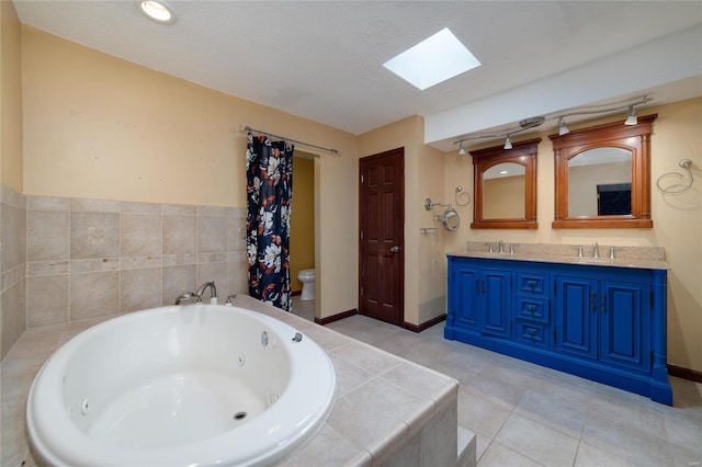 full bathroom featuring toilet, a sink, a tub with jets, a skylight, and double vanity