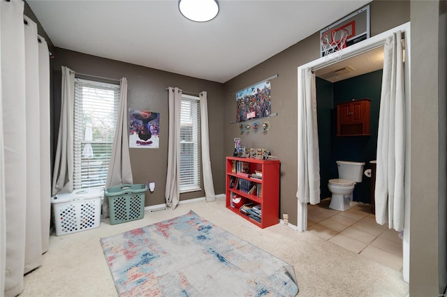 carpeted bedroom with connected bathroom, baseboards, and tile patterned flooring