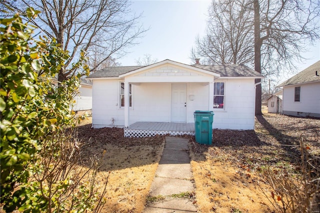 view of front of house with covered porch, concrete block siding, and roof with shingles